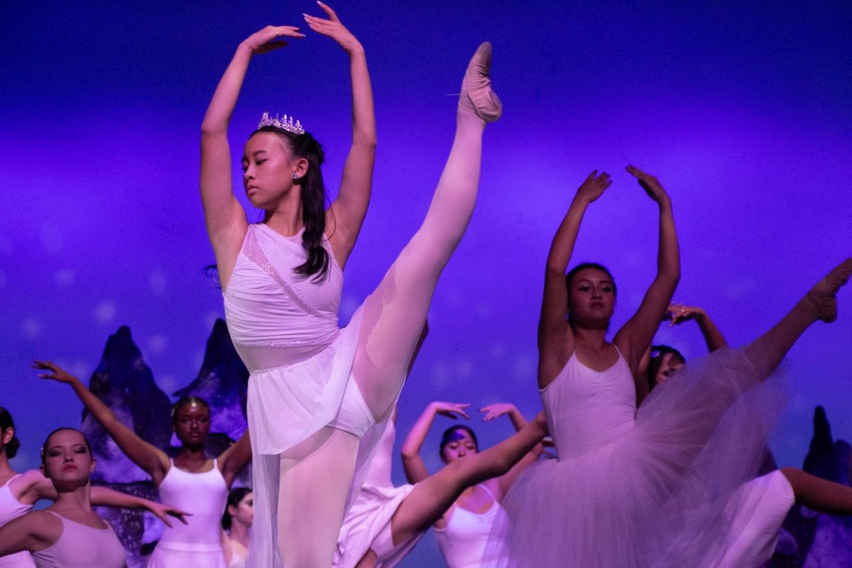 Dancers performing on stage under purple lighting